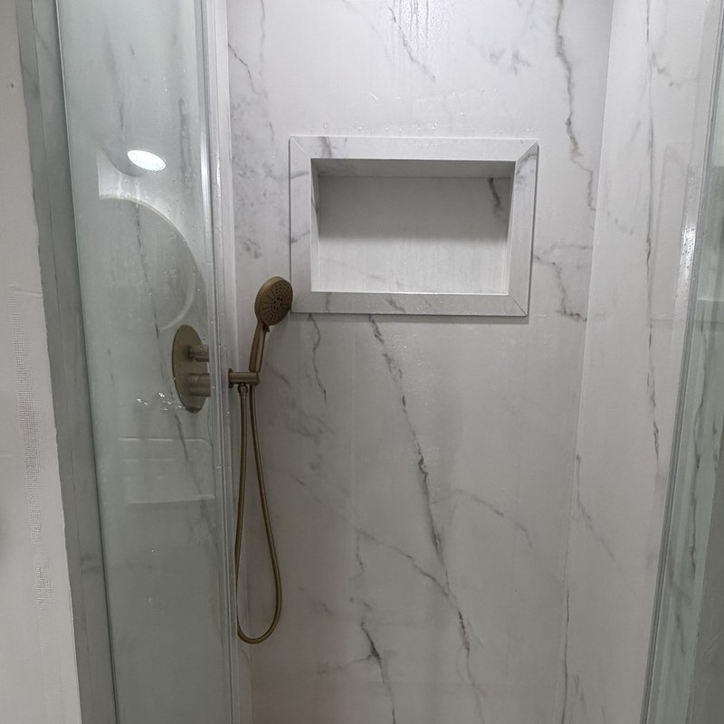 Completed Calacatta Oro shower with frameless glass and recessed niche