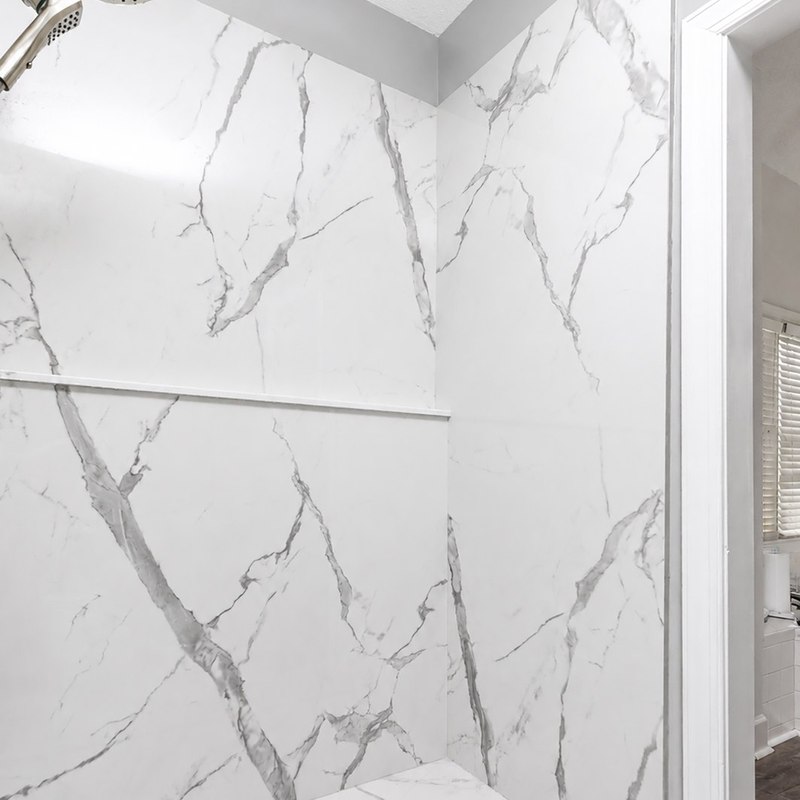 Statuario porcelain shower walls running continuously into the pan