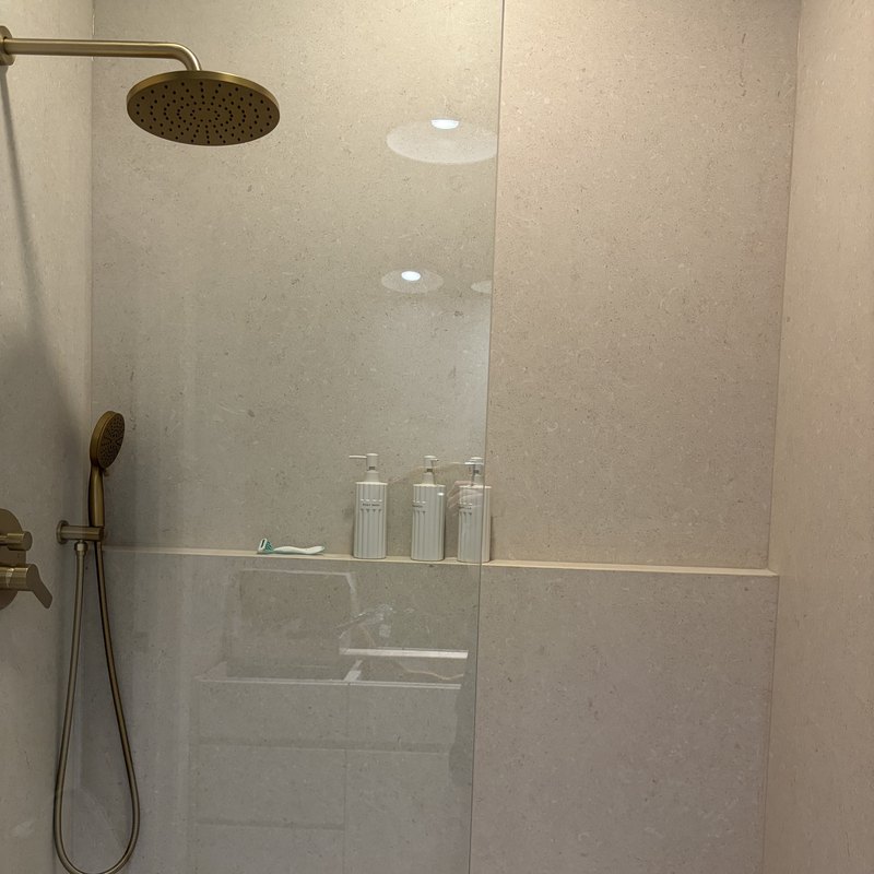 Rain head and handheld above a full-width porcelain ledge shelf.