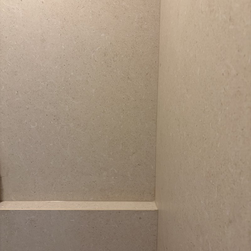 Corner joint where two ivory porcelain panels meet at the ledge.