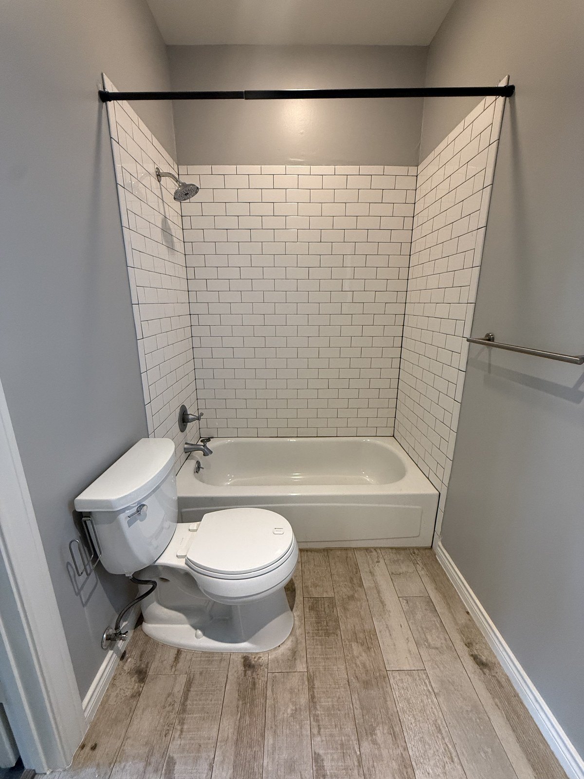 Subway-tiled alcove with a drop-in bathtub and a curtain rod.